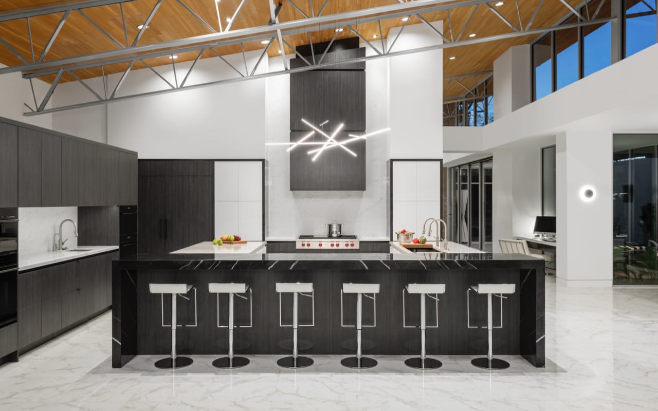 Contemporary industrial style kitchen with grey and white cabinets, steel ceiling beams and a modern light fixture.