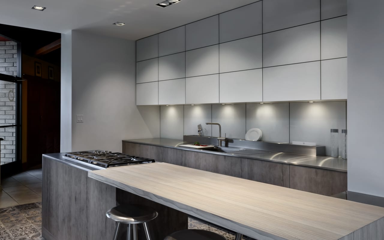 Contemporary kitchen with white upper cabinetry and a long grey island with a range.