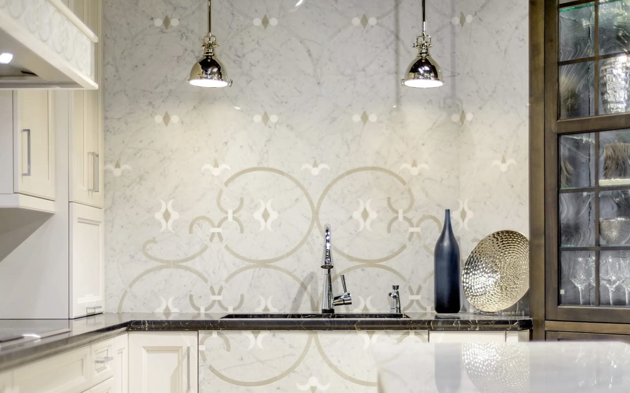 Kitchen with white geometric wallpaer, two pendant lights and a sink with a silver faucet.