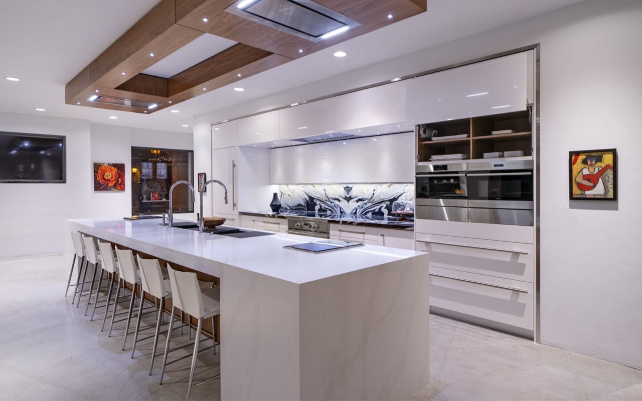 Contemporary kitchen with glossy white cabinets. A large white quartz kitchen island with seating for six.